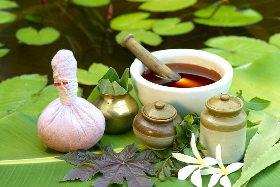 A herbal kizhi pouch, medicated oils and Ayurvedic preparations arranged on a banana leaf