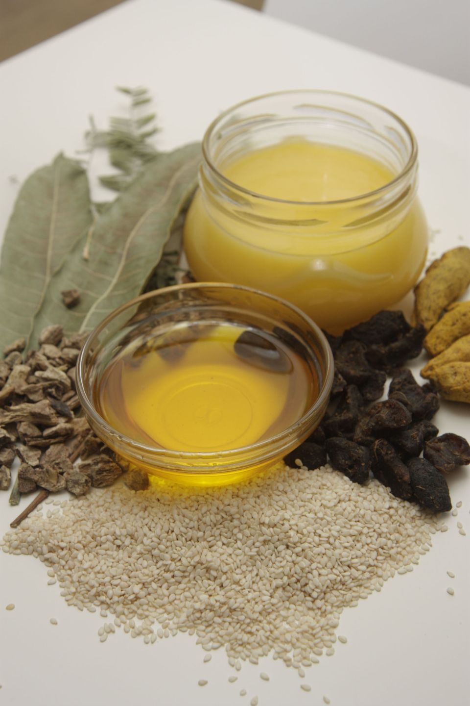Ayurvedic Therapy oils and ghee with medicinal herbs, sesame seeds and leaves