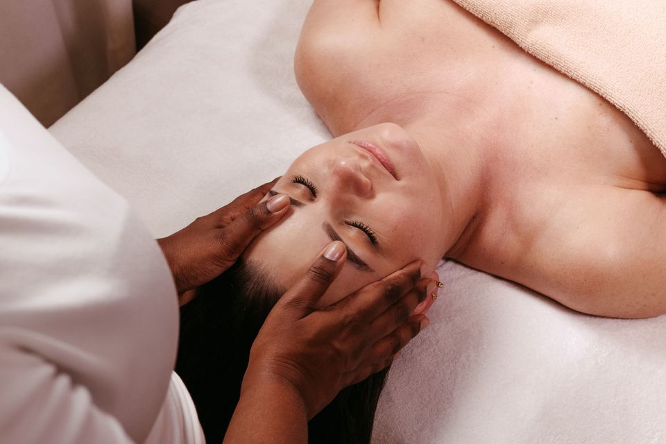 A woman receiving a gentle Ayurvedic Therapy face and head massage