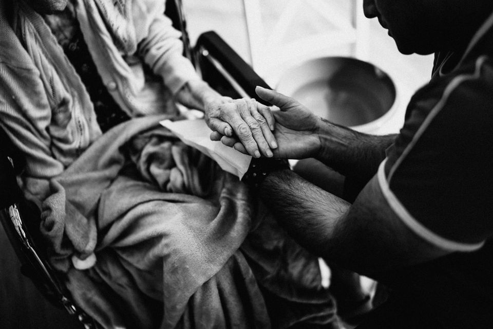 A caregiver gently holding a mother's hands in quiet support
